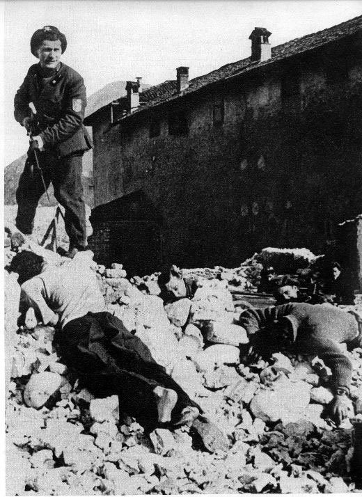 Un milite della RSI fotografato vicino ai corpi di alcuni partigiani uccisi durante un combattimento